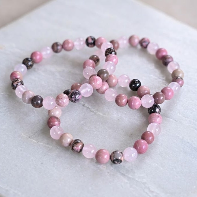 Set of pink and black beaded bracelets on a marble surface