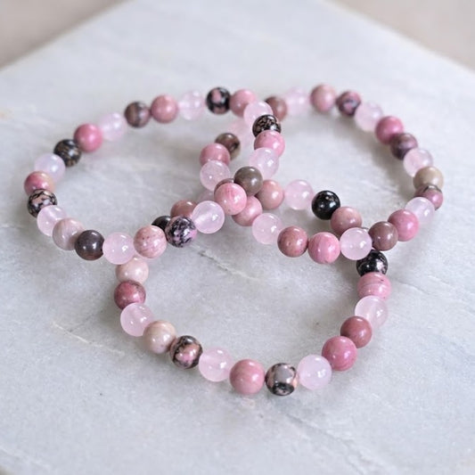 Set of pink and black beaded bracelets on a marble surface